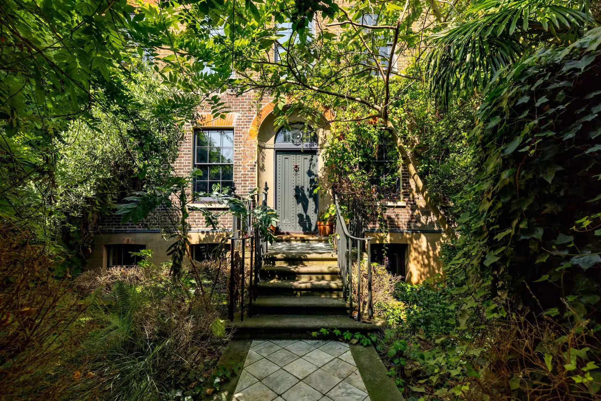 Brick house entrance surrounded by lush garden